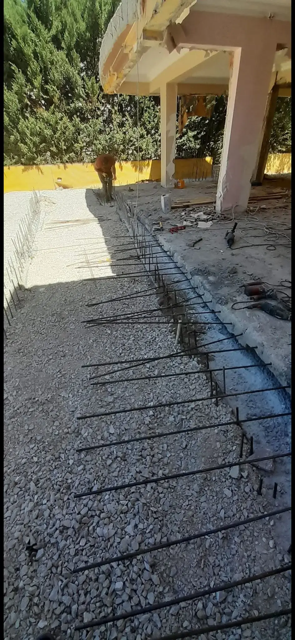 Mevcut beton kenarı boyunca sıra hâlinde ekilmiş filiz donatıları ve çakıl serilmiş yeni döküm alanı