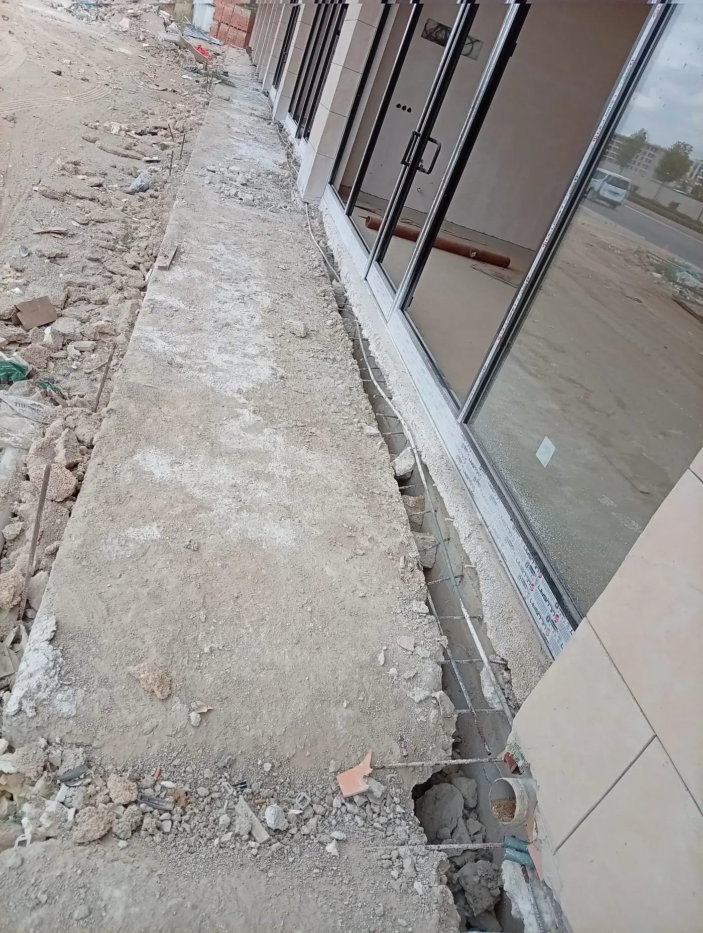 Cam cepheli bina boyunca uzanan, kenarı kırılarak donatısı açığa çıkarılmış beton şerit