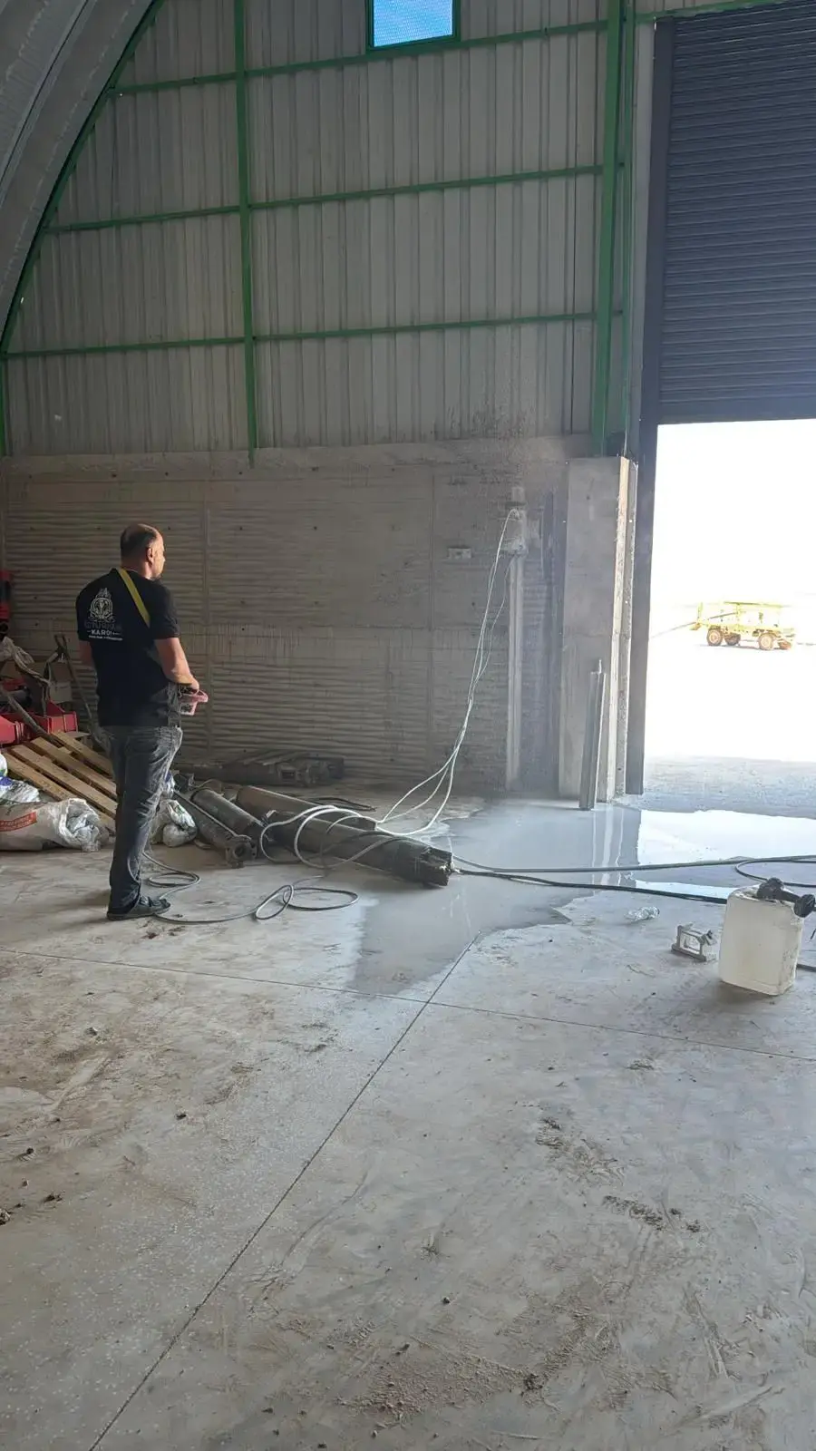 Çelik çatılı depo içinde prefabrik panel duvara kurulmuş duvar testeresi ve kumandayı tutan operatör